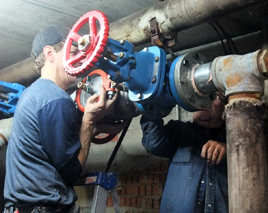 Plumbers installing 4-inch backflow preventer